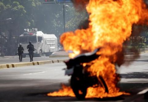 Riot security forces look on as a motorcycle bursts into flames during a rally against Venezuela's President Nicolas Maduro's government in Caracas, Venezuela, August 4, 2017. PHOTO BY REUTERS/Ueslei Marcelino