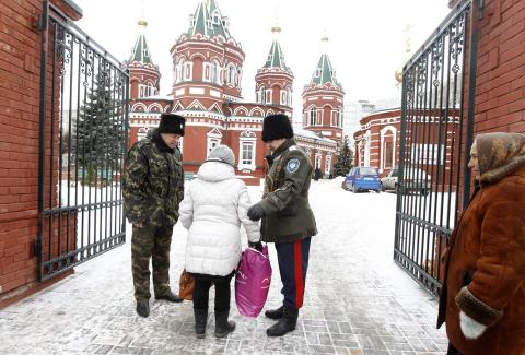 Russian Cossacks, who started regular patrols within the city in the wake of recent suicide attacks, check a woman's belongings in front of the Kazan Orthodox Cathedral in the southern Russian city of Volgograd