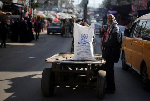 A Palestinian man stands next to a cart carrying a flour sack distributed by the United Nations Relief and Works Agency (UNRWA) in Khan Younis refugee camp in the southern Gaza Strip, January 3, 2018. PHOTO BY REUTERS/Ibraheem Abu Mustafa