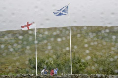 Scottish and English flags flutter in the wind and rain at the border between England and Scotland at Carter Bar