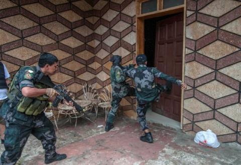 A joint group of police and military forces kick a door while conducting a house to house search. PHOTO BY REUTERS/Stringer