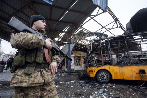 A member of the armed forces of the separatist self-proclaimed Donetsk People's Republic stands guard near a destroyed vehicle at a bus station after shelling in Donetsk, February 11, 2015. PHOTO BY REUTERS/Maxim Shemetov