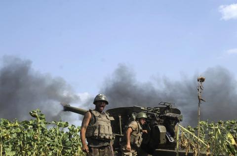 Ukrainian servicemen, who are members of an artillery section, gather near a cannon being fired during a military operation against pro-Russian separatists near Pervomaisk, Luhansk region