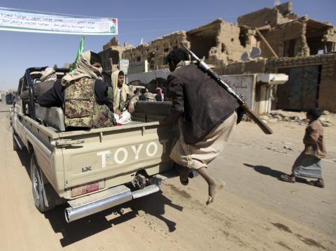 A follower of Yemen's Shi'ite Houthi group tries to climb into a car belonging to the group on the side of a road leading to the northwestern province of Saada