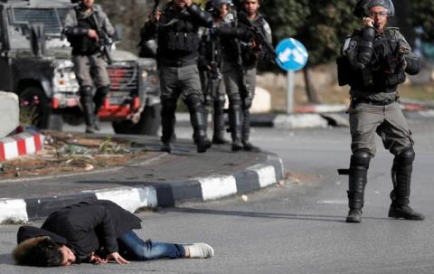 A Palestinian man lies on the ground after being shot by Israeli border policemen near the Jewish settlement of Beit El, near the West Bank city of Ramallah, December 15, 2017. PHOTO BY REUTERS/Goran Tomasevic