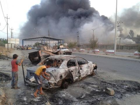 Civilian children stand next to a burnt vehicle during clashes between Iraqi security forces and al Qaeda-linked Islamic State in Iraq and the Levant (ISIL) in Mosul, Iraq, June 10, 2014. PHOTO BY REUTERS/Stringer