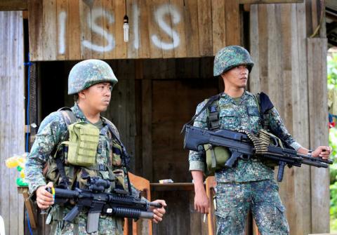 Soldiers stand guard along the main street of Mapandi village as government troops continue their assault on insurgents from the Maute group, who have taken over large parts of Marawi City, Philippines June 2, 2017. PHOTO BY REUTERS/Romeo Ranoco