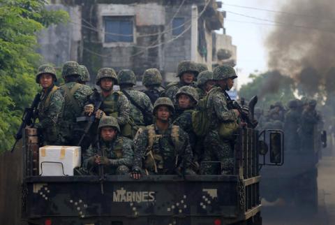 Soldiers onboard military trucks ride along the main street as government troops continue their assault on insurgents from the Maute group, who have taken over large parts of Marawi City, Philippines. PHOTO BY REUTERS/Romeo Ranoco