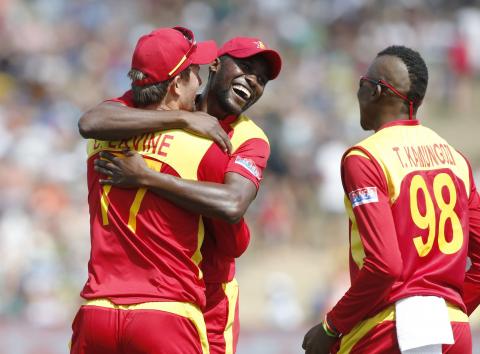 Zimbabwe's bowler Tafadzwa Kamungozi (R) celebrates with teammate Craig Ervine (L) and skipper Elton Chigumbura (C) after Ervine caught out South Africa's batsman AB de Villiers during their Cricket World Cup match in Hamilton, February 15, 2015. PHOTO BY REUTERS/Nigel Marple