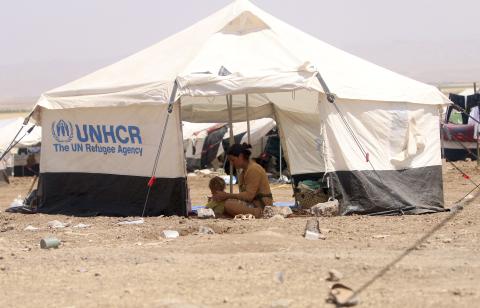 A refugee woman from the minority Yazidi sect, who fled the violence in the Iraqi town of Sinjar, sits with a child inside a tent at Nowruz refugee camp in Qamishli, northeastern Syria