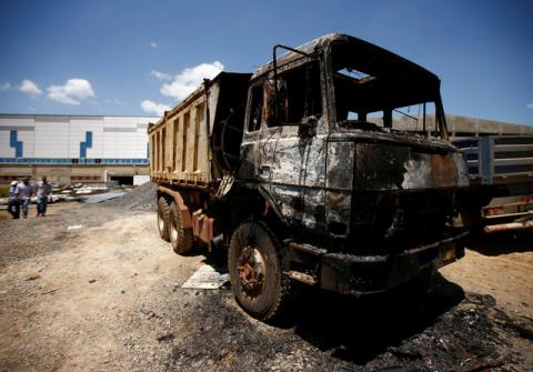People walk near a torched truck in the compound of a textile factory damaged by protests in the town of Sebeta, Oromia region, Ethiopia, October 8, 2016. PHOTO BY REUTERS/Tiksa Negeri