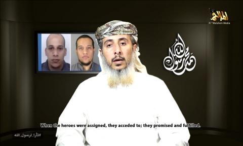 Nasser bin Ali al-Ansi, a leader of the Yemeni branch of al Qaeda (AQAP), speaks as an image of brothers Cherif Kouachi (rear L) and Said Kouachi (rear R), who carried out the Charlie Hebdo attack, is seen in this still image taken from a social media website, January 14, 2015. PHOTO BY REUTERS/YouTube via Reuters TV