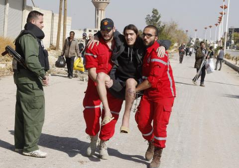 Volunteers from the Syrian Arab Red Crescent carry a sick man as Syrian families leave the besieged town of al-Moadamiyeh