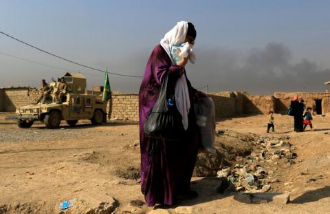 A woman who is fleeing the fighting between Islamic State and the Iraqi army in the Intisar district of eastern Mosul, walks past a military humvee while heading to safer territory in Iraq, November 7, 2016. PHOTO BY REUTERS/Zohra Bensemra