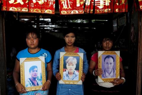 Women pose while holding portraits of their killed relatives (L-R) Aik Sai, Aik Maung and Aik Lort after their bodies were found in a grave last June at Mong Yaw village in Lashio, Myanmar, July 10, 2016. PHOTO BY REUTERS/Soe Zeya Tun