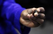 A Zimbabwean worker holds a piece of rough diamond from the country's Marange diamond fields, inside a polish and cutting shop in Harare, February 10, 2014. PHOTO BY REUTERS/Philimon Bulawayo