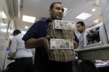 An employee carries money at an exchange office in downtown Cairo, June 5, 2014. PHOTO BY REUTERS/Amr Abdallah Dalsh