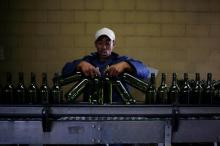 A worker loads wine bottles onto a conveyer belt at the Rostberg bottling plant near Cape Town, November 29, 2012. PHOTO BY REUTERS/Mike Hutchings
