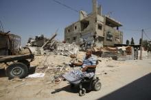 Palestinian maths teacher Ali Wahdan moves his motorised wheelchair past the ruins of his house, that witnesses said was destroyed by Israeli shelling during a 50-day war last summer, in Beit Hanoun town, in the northern Gaza Strip, July 6, 2015. PHOTO BY REUTERS/Suhaib Salem