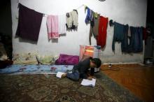 A Syrian refugee boy writes on the floor as his mother takes part in an interview with Reuters in Istanbul, Turkey, December 16, 2015. PHOTO BY REUTERS/Osman Orsal