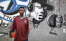 Fifteen-year-old Mamadou Doumbouya, a Talibe, or Islamic student, holds a begging bowl in front of a wall of graffiti in Senegal's capital Dakar. PHOTO BY REUTERS/Finbarr O'Reilly