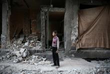 A boy stands near a damaged building after an airstrike yesterday in the rebel held Douma neighborhood of Damascus. PHOTO BY REUTERS/Bassam Khabieh
