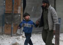 A man holds the hand of a boy as they flee deeper into the remaining rebel-held areas of Aleppo, Syria, December 9, 2016. PHOTO BY REUTERS/Abdalrhman Ismail