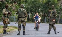 A local boy rides a bicycle towards Ukrainian government servicemen as they conduct a search for members of Right Sector in the village of Bobovyshche near Mukacheve, Ukraine, July 14, 2015. REUTERS/Stringer