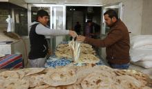 A customer (R) buys bread at a bakery in Baghdad, January 14, 2015. PHOTO BY REUTERS/Ahmed Saad
