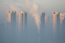 A chimney is seen in front of residential buildings during a polluted day in Harbin, Heilongjiang Province, China, January 21, 2016. PHOTO BY REUTERS/Stringer