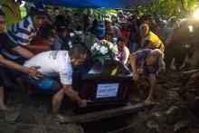 Relatives lower the coffin containing the body of Hayati Lutfiah, a passenger of AirAsia QZ8501, during her burial at a cemetery in Surabaya, January 1, 2015. PHOTO BY REUTERS/Sigit Pamungkas