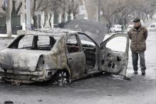 A man looks at a burnt car near a trolleybus stop in Donetsk, January 22, 2015. PHOTO BY REUTERS/Alexander Ermochenko