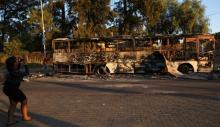 A women uses a cellphone to photograph the remains of a burnt out bus used to barricade roads by protesters in Atteridgeville a township located to the west of Pretoria, South Africa, June 21, 2016. PHOTO BY REUTERS/Siphiwe Sibeko