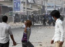 A worker throws a stone after clashes broke out during a protest in Phnom Penh