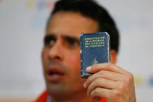 Venezuelan opposition leader and Governor of Miranda state Henrique Capriles holds a copy of the Venezuelan constitution while he talks to the media during a news conference in Caracas, Venezuela June 10, 2016. PHOTO BY REUTERS/Ivan Alvarado