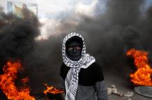A Palestinian demonstrator stands near burning tires during clashes with Israeli troops at a protest against U.S. President Donald Trump's decision to recognise Jerusalem as the capital of Israel, near the West Bank city of Nablus, December 15, 2017. PHOTO BY REUTERS/Mohamad Torokman