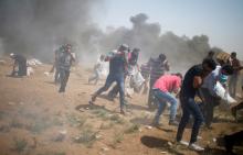 Palestinian demonstrators run for cover from tear gas fired by Israeli troops during a protest marking al-Quds Day, (Jerusalem Day), at the Israel-Gaza border, east of Gaza City, June 8, 2018. PHOTO BY REUTERS/Mohammed Salem