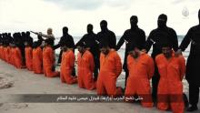 Men in orange jumpsuits purported to be Egyptian Christians held captive by the Islamic State (IS) kneel in front of armed men along a beach said to be near Tripoli, in this still image from an undated video made available on social media on February 15, 2015. PHOTO BY REUTERS/Social media