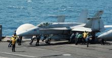 Sailors guide an F/A-18C Hornet assigned to the Valions of Strike Fighter Squadron (VFA) 15 on the flight deck of the aircraft carrier USS George H.W. Bush (CVN 77) in the Gulf
