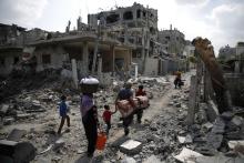 A Palestinian family carries their belongings towards the remains of their destroyed home after returning to Beit Hanoun town, which witnesses said was heavily hit by Israeli shelling and air strikes during the Israeli offensive, in the northern Gaza Strip