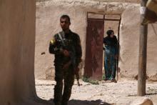A Syria Democratic Forces (SDF) fighter stands near a woman looking out a doorway in a village, on the outskirts of Manbij city, after they took control of it from Islamic State forces, Aleppo province, Syria, June 8, 2016. PHOTO BY REUTERS/Rodi Said