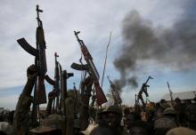 Rebel fighters hold up their rifles as they walk in front of a bushfire in a rebel-controlled territory in Upper Nile State, South Sudan February 13, 2014. PHOTO BY REUTERS/Goran Tomasevi