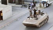 Militant Islamist fighters hold the flag of Islamic State (IS) while taking part in a military parade along the streets of northern Raqqa province in this June 30, 2014 file photo. PHOTO BY REUTERS/Stringer