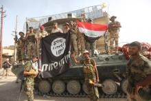 Shi'ite fighters and Iraqi security forces hold an Islamic State flag (L), which they pulled down after clashes with IS militants, in Saqlawiya, north of Falluja, Iraq, June 4, 2016. PHOTO BY REUTERS/Stringer