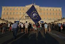 A protester holds a European Union flag with the Euro logo during a Pro-Euro rally in front of the parliament building in Athens, Greece, July 9, 2015. PHOTO BY REUTERS/Yannis Behrakis