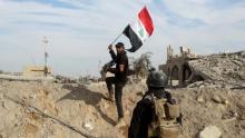 A member from the Iraqi security forces holds an Iraqi flag in the city of Ramadi, December 27, 2015. PHOTO BY REUTERS/Stringer