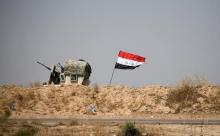 A military vehicle of the Iraqi security forces is seen next to an Iraqi flag in Falluja, Iraq, June 13, 2016. PHOTO BY REUTERS/Thaier Al-Sudani
