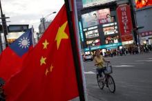 A woman rides a bike past Taiwan and China national flags during a rally held in Taipei, Taiwan, May 14, 2016. PHOTO BY REUTERS/Tyrone Siu