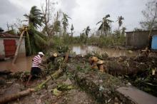A man cuts branches off fallen trees in a flooded area by a river after Hurricane Matthew in Les Cayes, Haiti, October 5, 2016. PHOTO BY REUTERS/Andres Martinez Casares