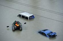 A rescue boat approaches a submerged car on a flooded street after heavy rainfall. PHOTO BY REUTERS/Stringer